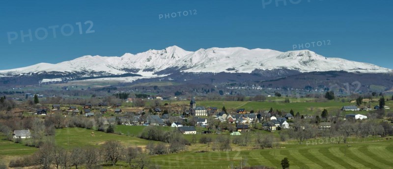Regional natural park of the Volcanoes of Auvergne. View on the village of Saint Genes Champespe and the Monts Dore in winter. Puy de Dome department. Auvergne-Rhone-Alpes. France