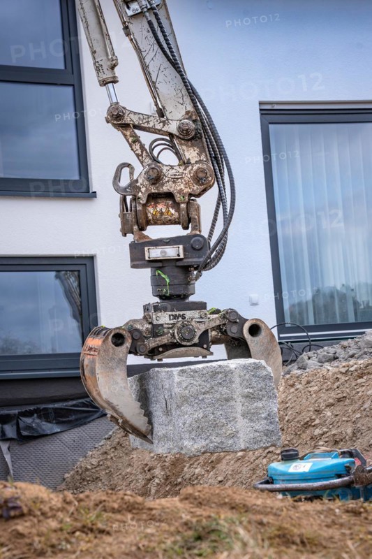 Excavator grab with stone on construction site