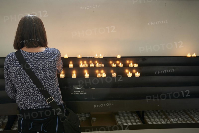Woman in front of offering candles in church