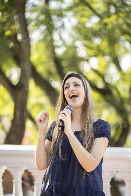 Young blonde woman singing in the street. Singer performing in the street