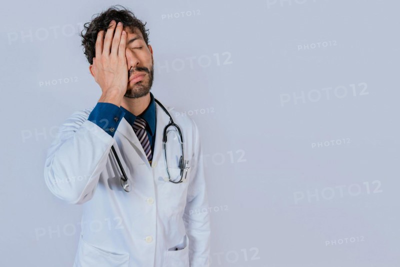 Exhausted doctor with hand on his forehead. Overworked doctor with hand on forehead isolated