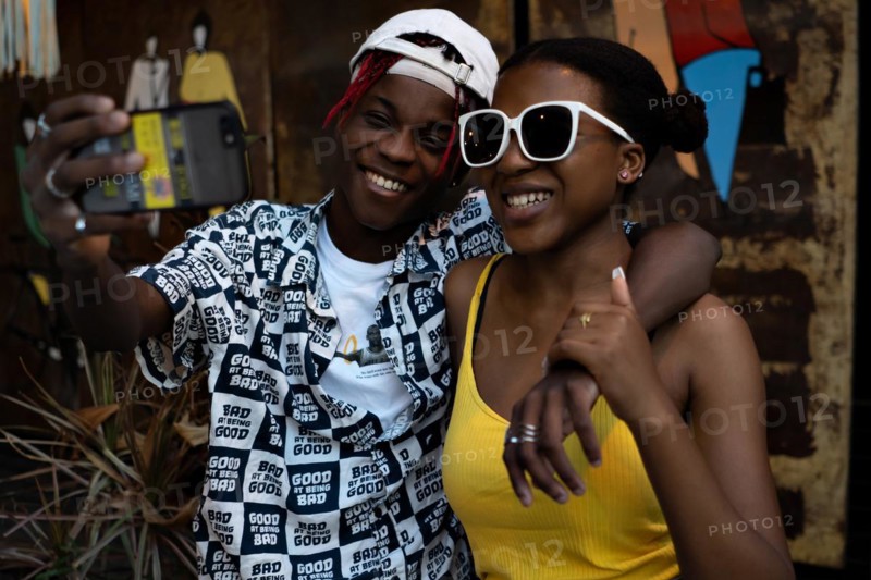 Young African-American couple taking a selfie and laughing. Friends with modern style having fun and posing
