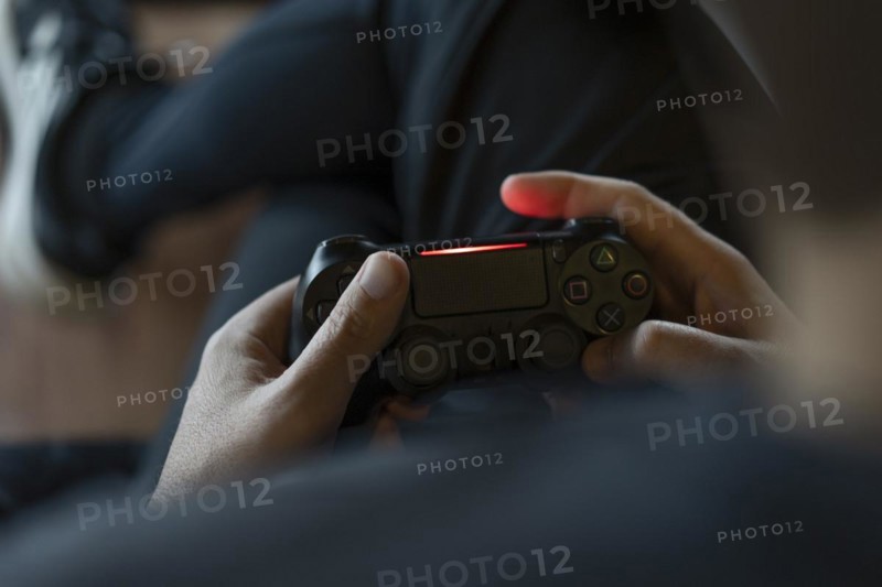 Close-up of an adult man's hands holding a joystick while playing a video game on a console