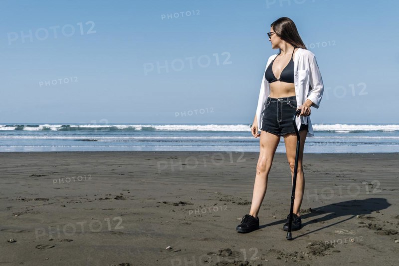 Young woman with cane looking at the sea. Cancer survivor
