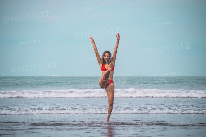 Young woman in red bikini having fun and feeling free in the turquoise sea