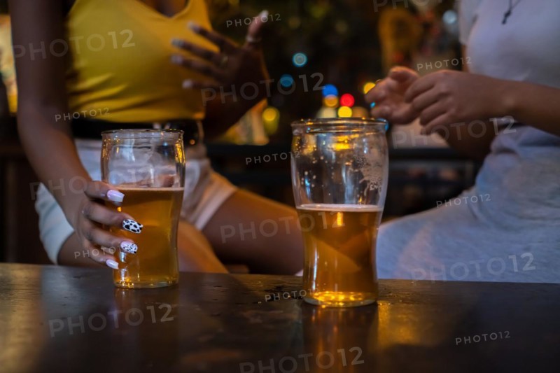 Two friends drinking beer. Detail shot of beer glasses without faces. Unrecognized people