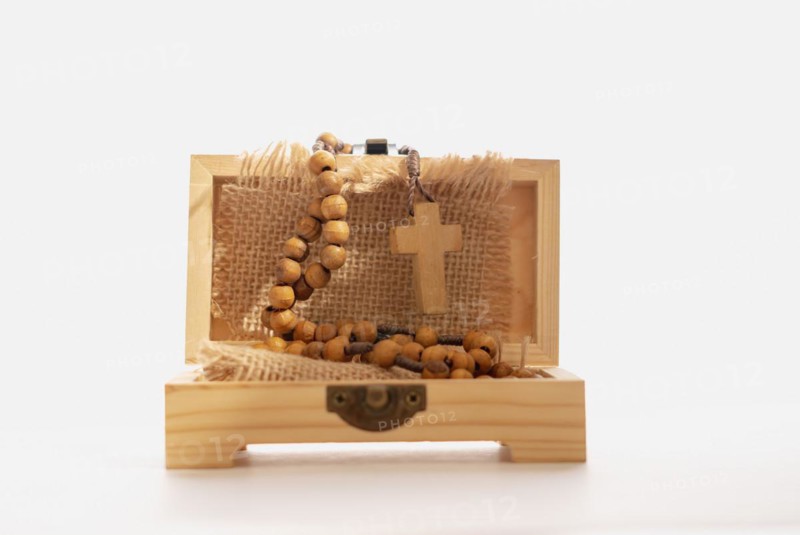 Close-up of a wooden box with a Christian crucifix wrapped in a raffia cloth isolated on a white background