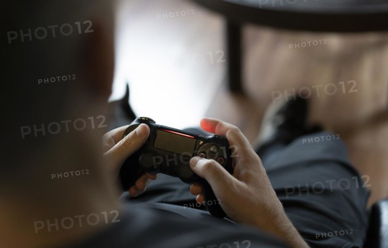 Close-up of an adult man's hands holding a joystick while playing a video game on a console. Copy space