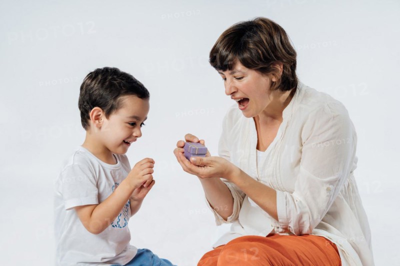 Happy mother's day! Son congratulating his mom and giving her a gift. Studio portrait on white background
