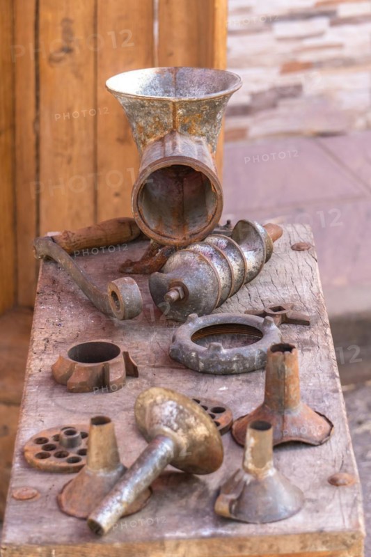 Antique sausage making machine with all its accessories on a wood table