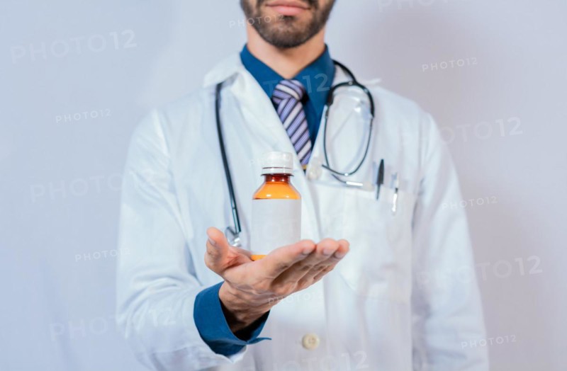 Doctor's hand holding a bottle of syrup. Doctor showing a bottle of syrup