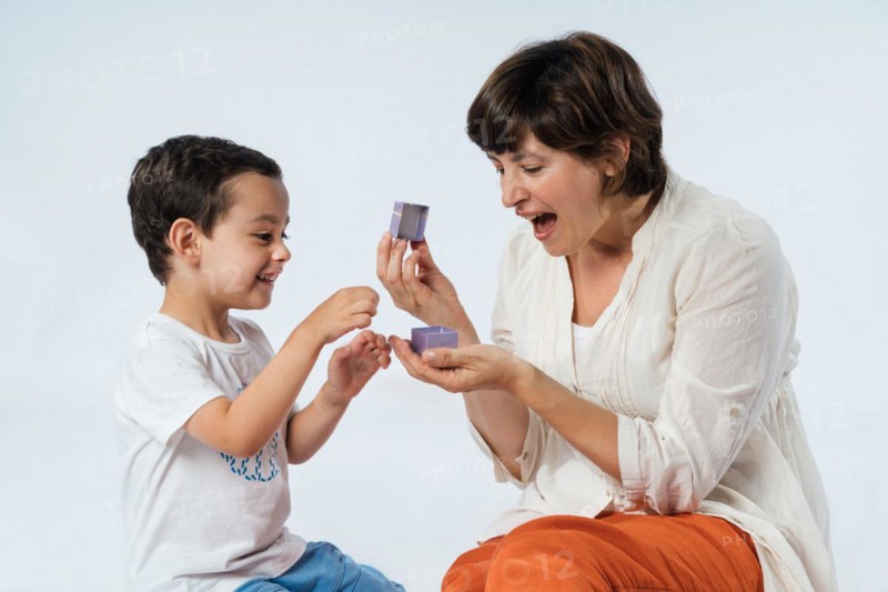 A young child surprises his mother with a birthday gift. Mum's birthday. Mother's day concept. Boy expressing gratitude and love on mother's day