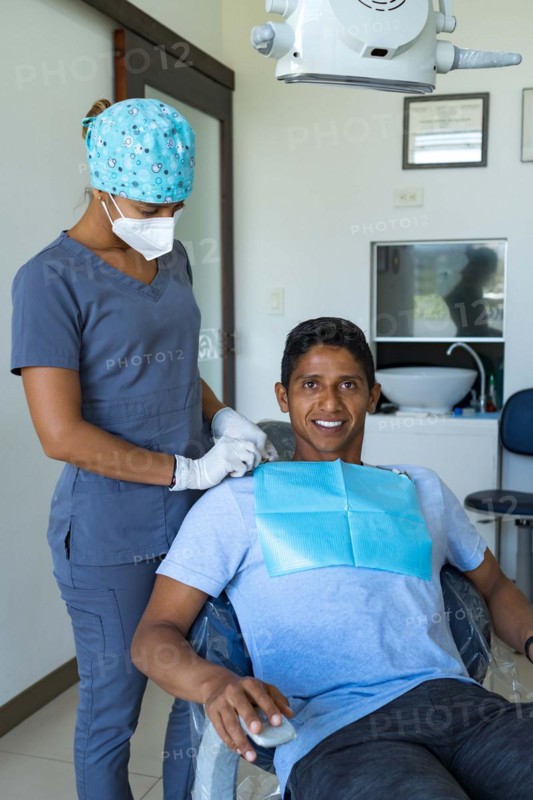 Female dentist in dental office talking with young male patient and preparing for treatment
