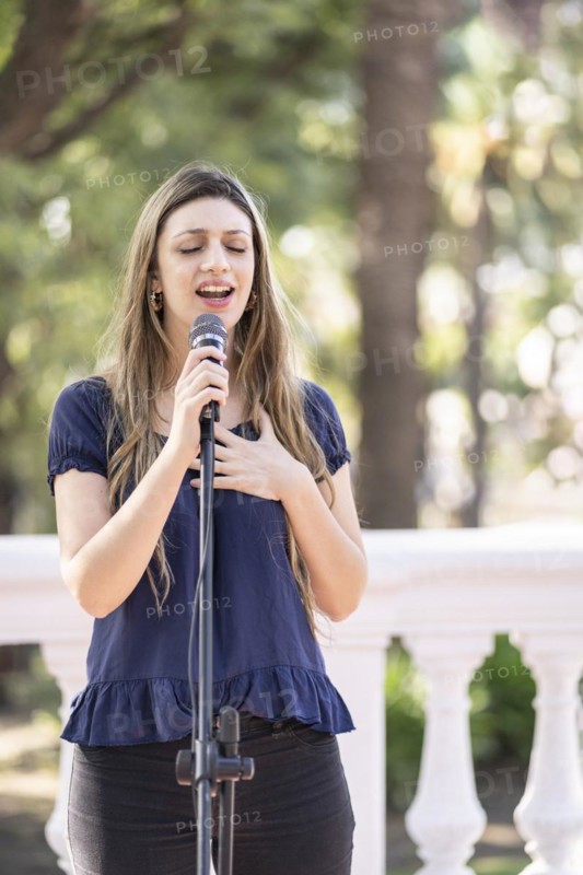 Young blonde woman singing in the street. Singer performing in the street