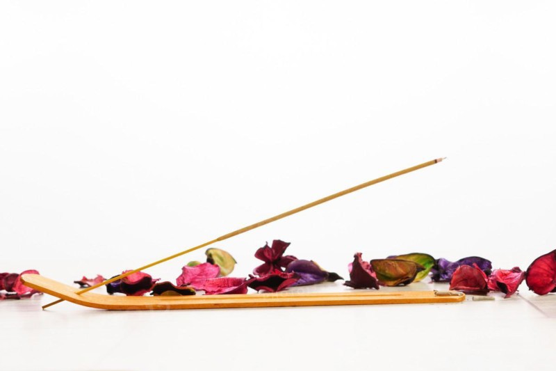 Close-up of incense stick isolated on white background with colorful flower petals