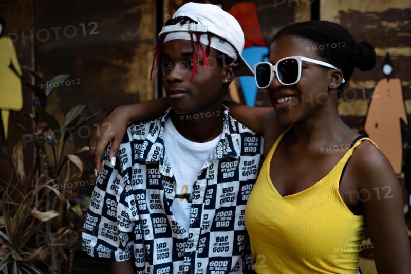 Positive African American youth hugging each other wearing fashionable clothes