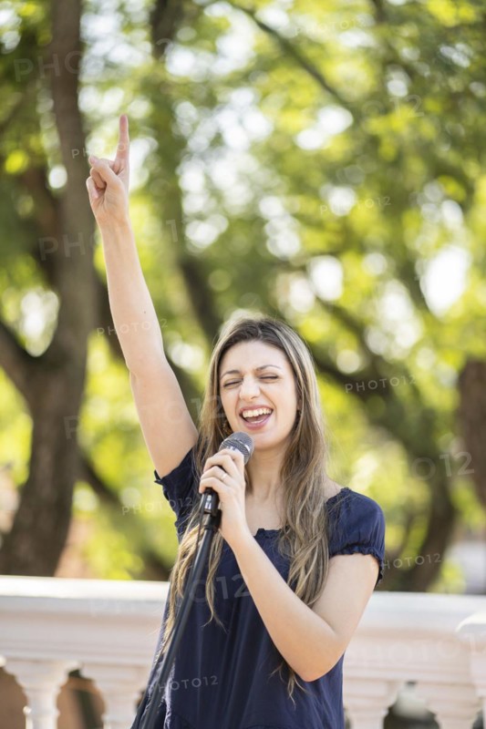 Young blonde woman singing in the street. Singer performing in the street
