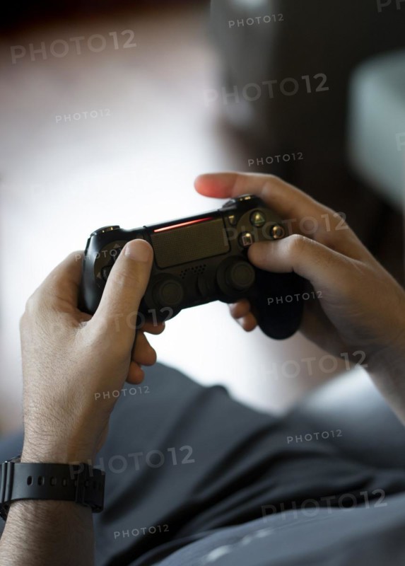 High angle view of an adult man's hands holding a joystick while playing a video game on a console
