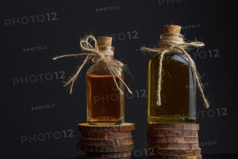 Glass bottles with olive oil on wooden discs isolated on black background and copy space