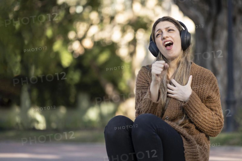 Blonde woman sitting on the street listening to music