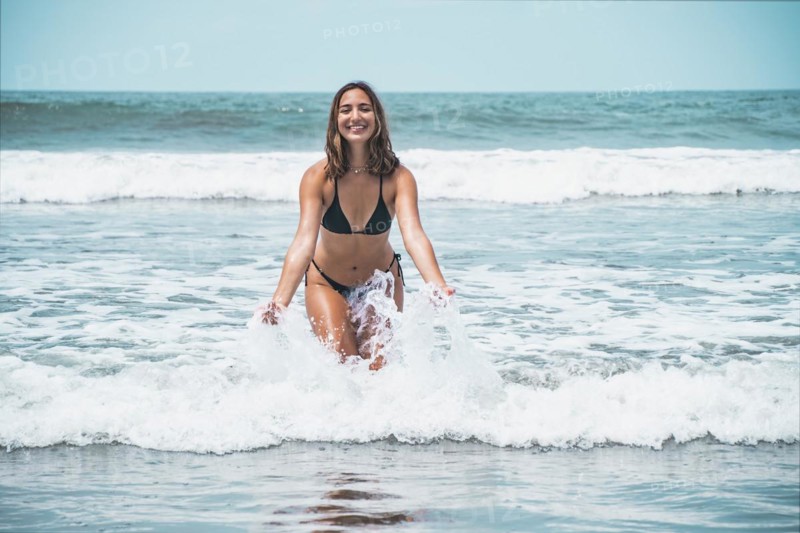 Portrait of beautiful young woman splashing in turquoise sea