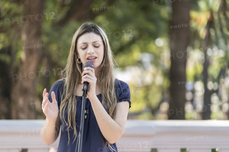 Young blonde woman singing in the street. Singer performing in the street
