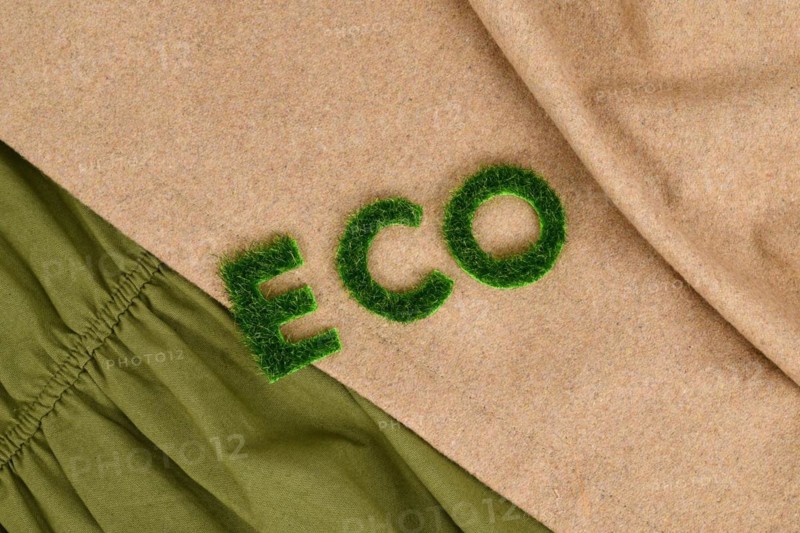 Concept for environmental friendly produced clothing with text 'ECO' made out of grass on textiles