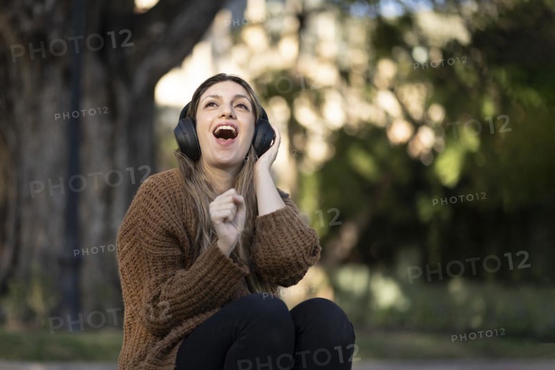 Blonde woman sitting on the street listening to music