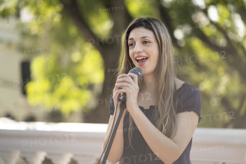 Young blonde woman singing in the street. Singer performing in the street