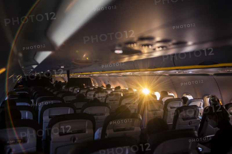 The sun shines into a window of a plane with travellers to Frankfurt