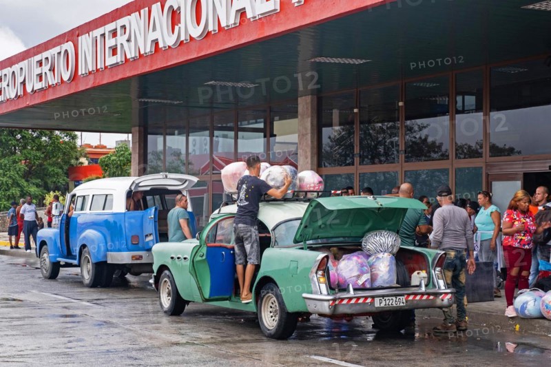 Cubans loading their old American cars with loads of imported foreign merchandise in front of the Antonio Maceo Airport in the city Santiago de Cuba