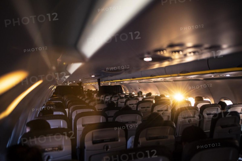 The sun shines into a window of a plane with travellers to Frankfurt