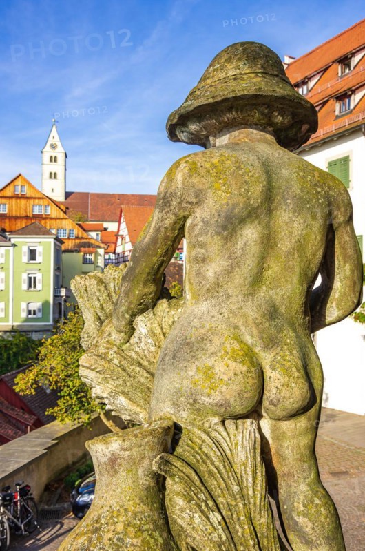 View of the naked buttocks of a male stone sculpture across the castle square to the Church of the Visitation of the Virgin Mary