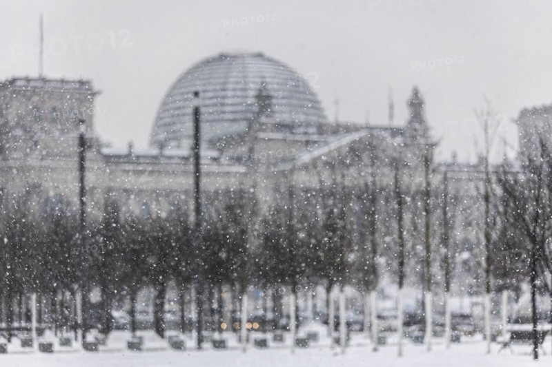The Reichstag building is silhouetted against snowfall in the government district in Berlin