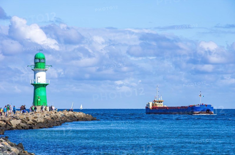 Lighthouse and seafaring romance on the west pier while the cargo ship Munin R passes the harbour entrance