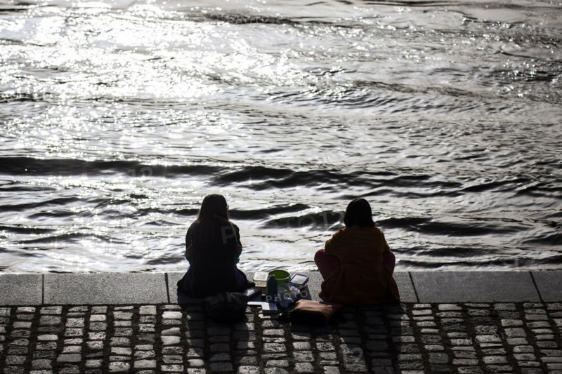 Two woman relaxing in the midday sun at the Spreebogen in the government district in Berlin
