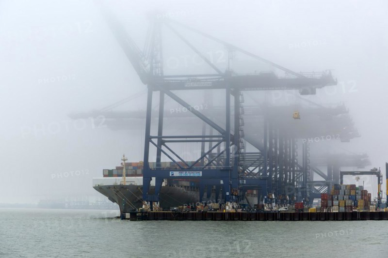 Foggy weather low visibility container ship cranes at quayside