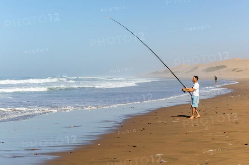 Fisherman standing by Atlantic Ocean