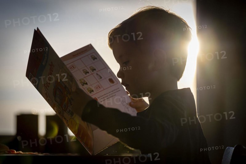 Symbolic photo: A little boy looks at a picture book. Berlin