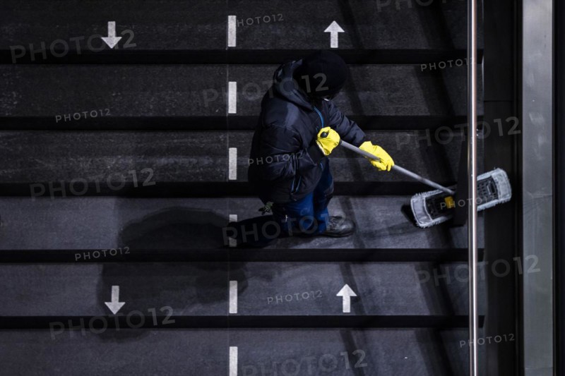A cleaner wipes a staircase marked with arrows for the respective walking directions
