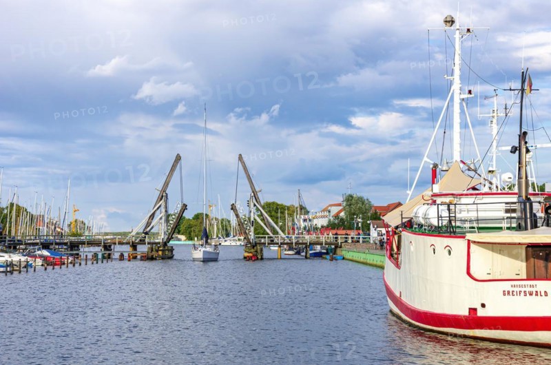 A sailboat is about to pass the old historic wooden bascule bridge in the city harbour of Greifswald-Wieck