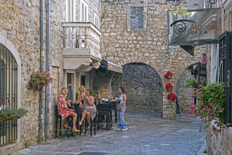 Montenegrin locals having a drink outside cafe in the medieval Old Town centre of the city Budva along the Adriatic Sea