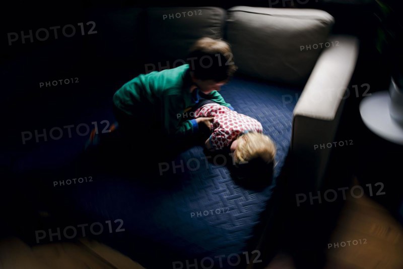 Symbolic photo on the subject of quarrels between siblings. A two-year-old girl and a five-year-old boy fight on a couch at home. Berlin