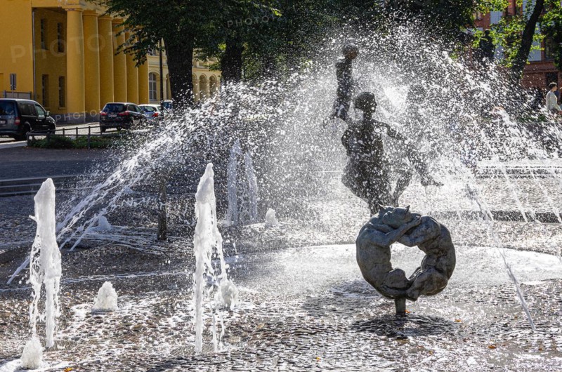 Urban scene at the fountain of joie de vivre on the Universitaetsplatz in the backlight