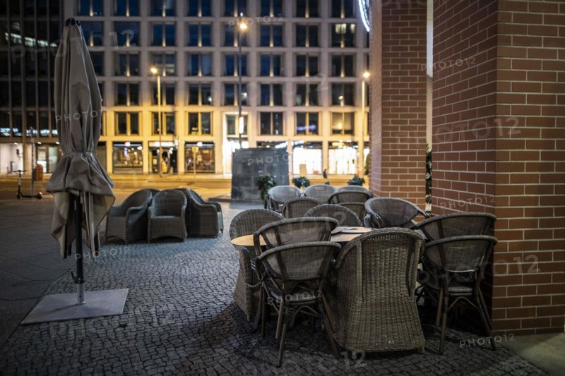 Unused furniture standing in front of a cafe at Potsdamer Platz in Berlin in the evening