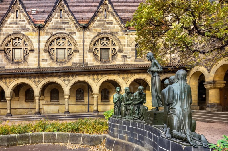 Court of honour with arcades and group sculpture of the Consoling Christ by Selmar Werner. The church