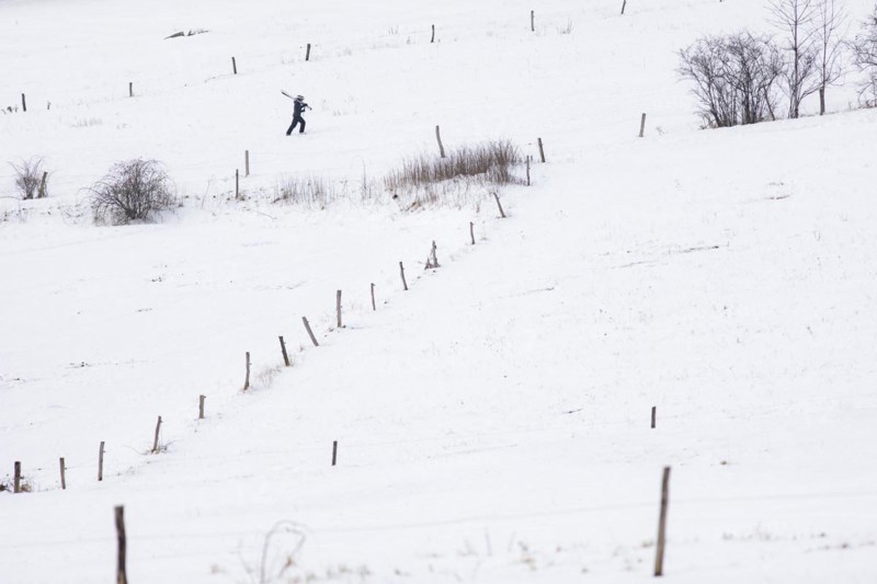 A boy carries skis up a slope in Koenigshain