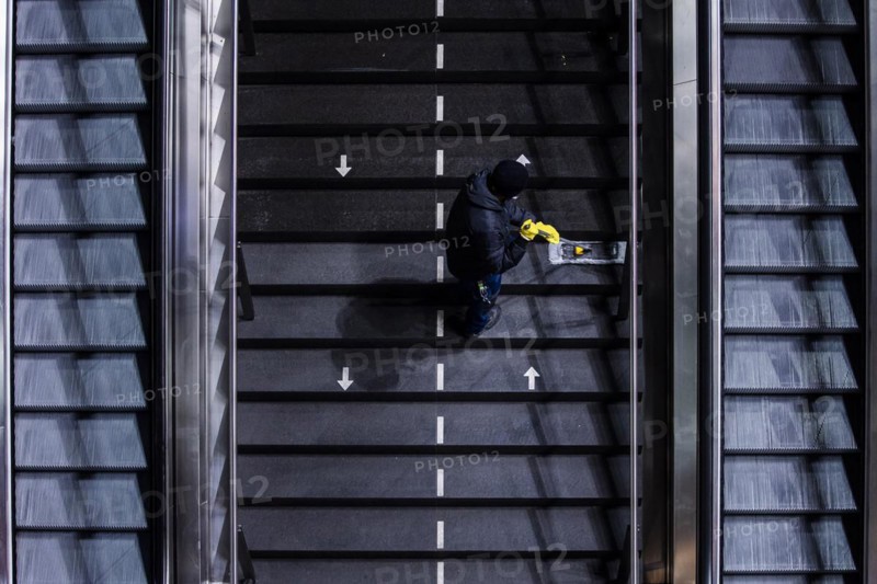 A cleaner wipes a staircase marked with arrows for the respective walking directions