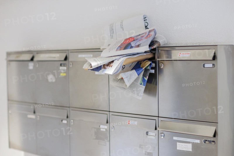 Newspapers and letters stuck in the opening of a crowded letterbox. Berlin