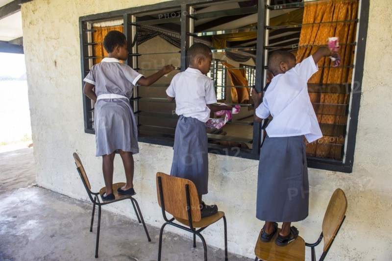 School kids cleaning the windows of their school